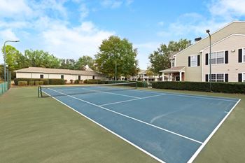 Blue tennis court with houses in the background at The Enclave at Crossroads, Raleigh, North Carolina